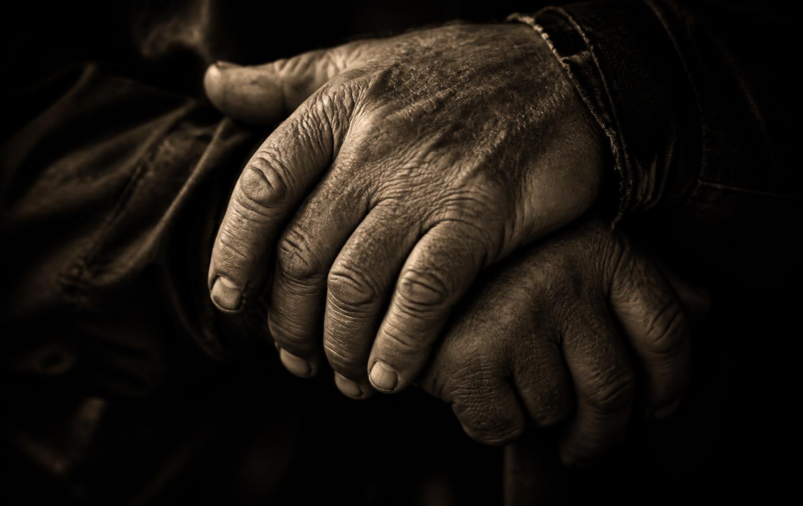 Weathered hands resting on stone